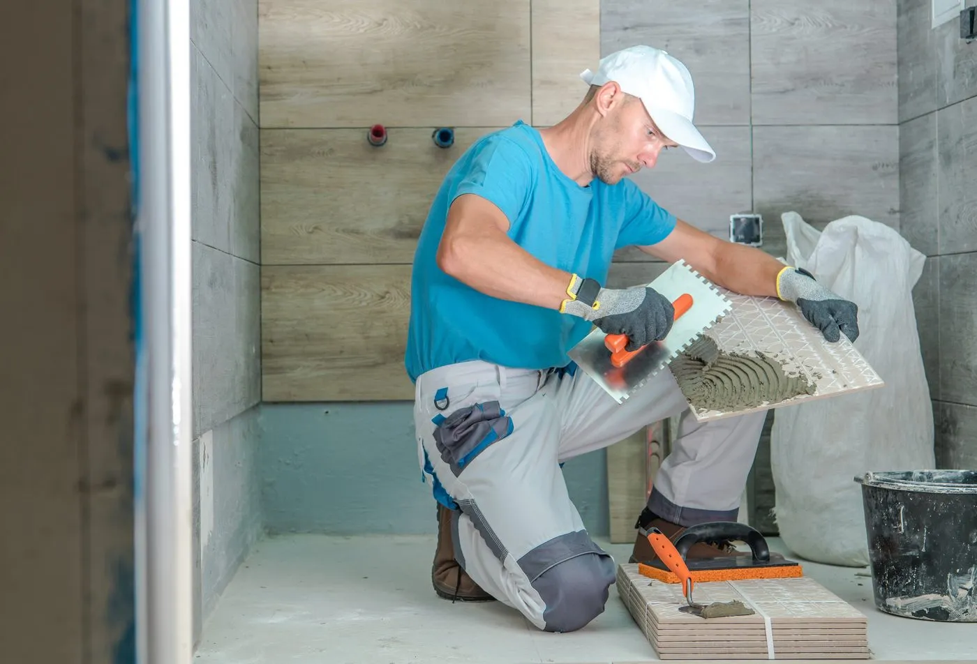 Tile installer laying wall tiles in a bathroom