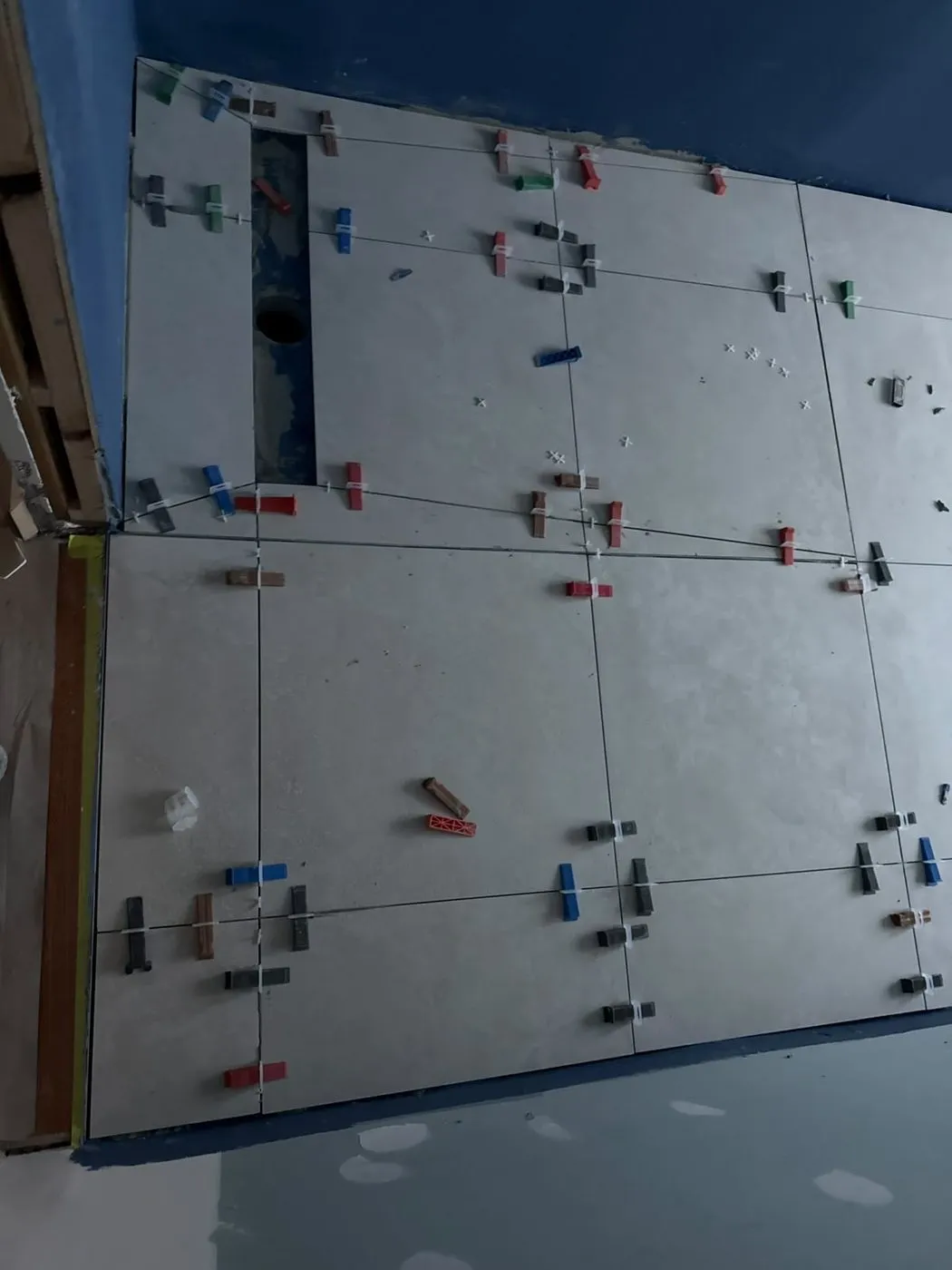 Large-format floor tiles laid with levelling spacers