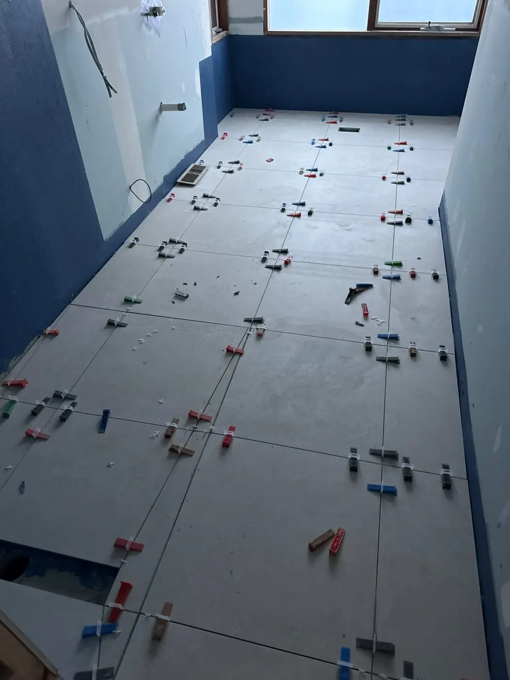 Floor tiles being laid in a bathroom under renovation